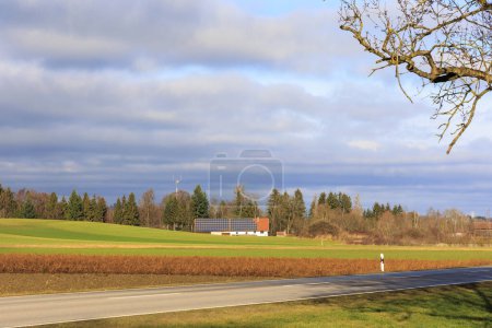 Photo for View of an agricultural property at the edge of a forest with a large photovoltaic system near Utting under cloudy skies - Royalty Free Image