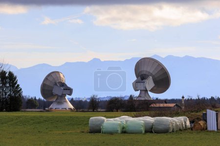 Foto de Parabolic antennas of the satellite communication system of the earth station near Raisting at the Ammersee in partly cloudy sky in front of the panorama of the Alps - Imagen libre de derechos