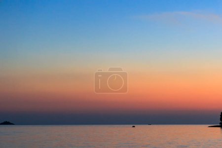 Photo for Fishing boats sail across the sea near Rovinj in Croatia at dusk while a narrow crescent of the waxing moon is in the sky - Royalty Free Image