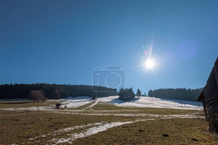 Foto de The sun shines from a blue sky over a ski lift that is out of service due to lack of snow near Steingaden, Bavaria - Imagen libre de derechos