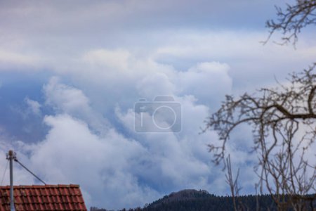 Photo for Rays of sunlight break through a dense cloud cover over a wooded landscape near Ravensburg in Baden-Wrtemberg on a cloudy day in winter. - Royalty Free Image