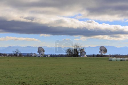 Foto de Parabolic antennas of the satellite communication system of the earth station near Raisting at the Ammersee in partly cloudy sky in front of the panorama of the Alps - Imagen libre de derechos