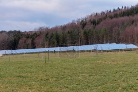 Photo for Solar park in a rural environment in front of a railroad line in Gaishaus near Ravensburg in Baden Wrtemberg on a cloudy day in winter. - Royalty Free Image