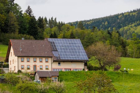 Foto de Montañas y casas rurales con módulos fotovoltaicos en el techo bajo el cielo nublado en Gresgen en la Selva Negra - Imagen libre de derechos