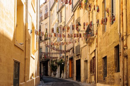 Photo for A narrow alley decorated with colorful flags in the downtown of the French city of Montpellier in France - Royalty Free Image