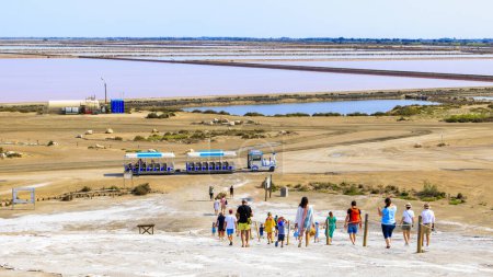 Photo for Visitors at the pink salt pans of salt production near the town of Aigues-Mortes in the Camarque region of France, 30.05.2023 - Royalty Free Image