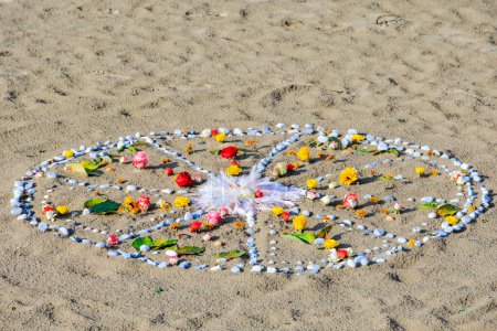 Téléchargez les photos : Round mandala ornament made of stones flowers and feathers on sandy beach - en image libre de droit