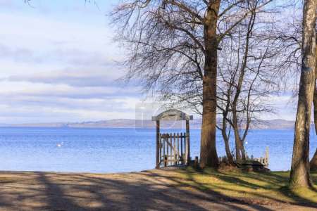 Gate with a weathered sign on the shore of Ammersee under trees in winter near Dieen in Bavaria.