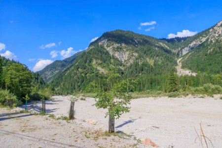 Téléchargez les photos : Lit de rivière sec du ruisseau Torsulenbach dans la vallée d'Ammertal près du lac Plansee en Autriche par une journée ensoleillée avec un ciel bleu. - en image libre de droit