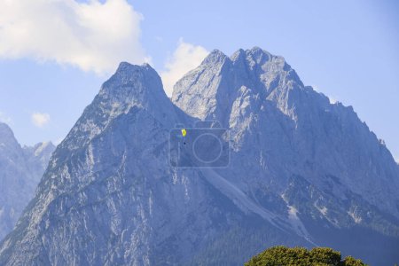Foto de El macizo de Zugspitz en las montañas de Wetterstein con parapentes vistos desde Garmisch-Partenkirchen en un día soleado - Imagen libre de derechos