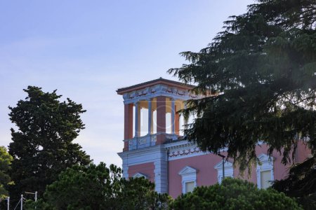 Téléchargez les photos : Ancienne magnifique maison résidentielle parmi les conifères par une journée ensoleillée avec ciel bleu dans la ville croate Rovinj - en image libre de droit