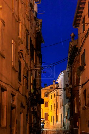 Foto de Calles de la ciudad vieja en la ciudad croata Rovinj por la noche con alumbrado público y señales con texto croata - Imagen libre de derechos