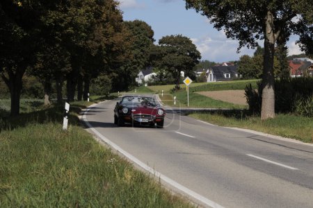 Téléchargez les photos : Rouge Jaguar E-Type des années 70 conduite sur une route de campagne près du château de Blumenthal lors du rallye automobile classique Fuggerstadt Classics, Allemagne, Augsbourg, 24 septembre 2023 - en image libre de droit