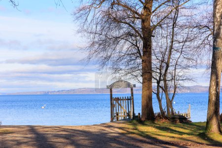 Foto de Gate with a weathered sign on the shore of Ammersee under trees in winter near Dieen in Bavaria. - Imagen libre de derechos