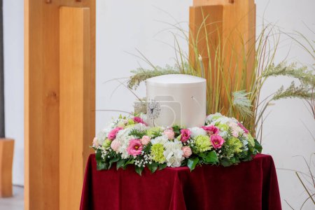 Geschmückte Urne mit Asche im Blumenkranz bei Beerdigung
