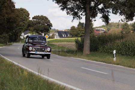 Foto de Red Volvo PV 444 ES from the 60's driving on a country road near Blumenthal Castle during the classic car rally Fuggerstadt Classics, Germany, Augsburg, September 24, 2023 - Imagen libre de derechos
