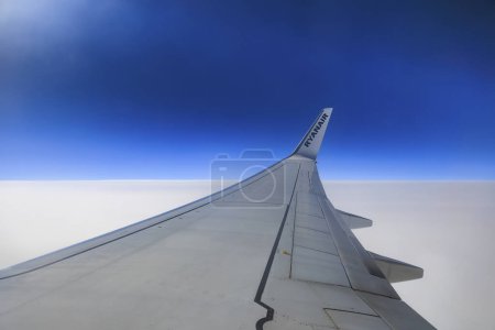 Photo for Memmingen, Germany 20.10.2023, right wing of a Ryanair Boing 737-800 in blue skyat cruising altitude above a closed cloud cover - Royalty Free Image