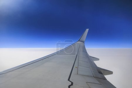 Photo for Memmingen, Germany 20.10.2023, right wing of a Ryanair Boing 737-800 in blue skyat cruising altitude above a closed cloud cover - Royalty Free Image