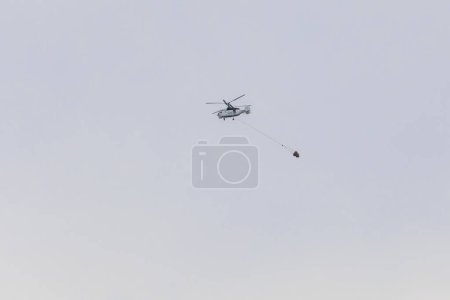 Foto de Helicóptero con tanque de agua apagado adjunto luchando contra un incendio forestal en la isla de Corfú - Imagen libre de derechos