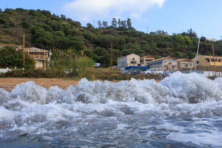 Téléchargez les photos : La mer aux couleurs bleues et vertes avec des vagues qui s'écrasent lors d'une journée orageuse à Agios Georgios sur l'île de Corfou - en image libre de droit