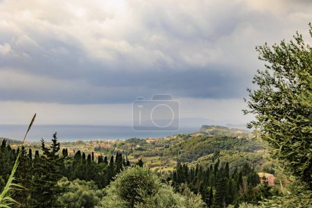 Téléchargez les photos : Vue sur les collines boisées et les oliviers près de Sidari sur l'île de Corfou sous un ciel nuageux - en image libre de droit