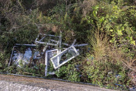 Téléchargez les photos : Vieilles fenêtres ont été jetées comme des ordures dans les buissons à côté d'une route sur l'île de Corfou - en image libre de droit