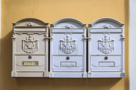 Téléchargez les photos : Trois boîtes aux lettres blanches sur un mur jaune dans la ville de Corfou sur l'île de Corfou - en image libre de droit
