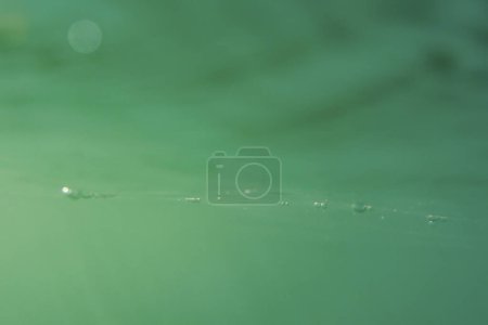 Téléchargez les photos : Bulles d'air et faisceaux lumineux tombent à travers la surface de la mer dans l'eau bleue verte - en image libre de droit