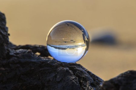Téléchargez les photos : Le coucher du soleil et la plage et la mer de la baie d'Agios Georgios sur l'île de Corfou se reflètent dans une sphère de verre - en image libre de droit