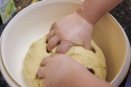 Photo for A child's hands knead dough for Christmas biscuits in a bowl - Royalty Free Image