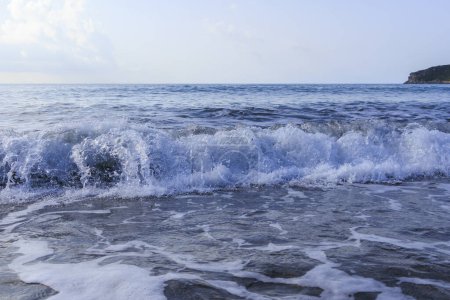 Téléchargez les photos : La mer aux couleurs bleues et vertes avec des vagues qui s'écrasent lors d'une journée orageuse à Agios Georgios sur l'île de Corfou - en image libre de droit