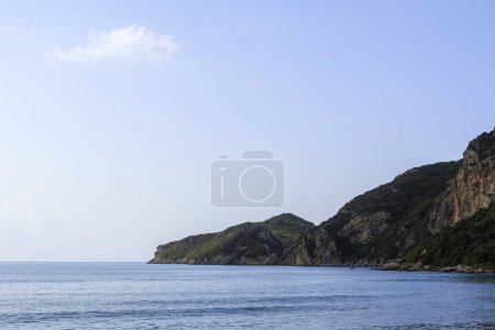 Téléchargez les photos : Plage de sable au bord de la mer près d'Agios Georgios sur l'île de Corfou sous un ciel bleu - en image libre de droit