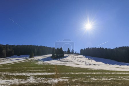 Téléchargez les photos : The sun shines from a blue sky over a ski lift that is out of service due to lack of snow near Steingaden, Bavaria - en image libre de droit