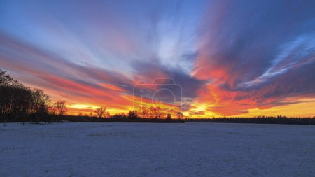 Photo for Colourful sunrise with glowing red clouds on a winter's day over the meadows and forests of Siebenbrunn, the smallest district of the Fugger city of Augsburg - Royalty Free Image