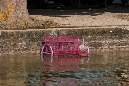 Photo for A park bench is flooded by high water and stands in the water while the waves splash over it - Royalty Free Image