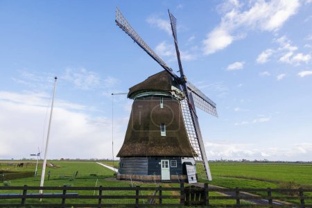 Foto de Un molino de viento holandés típico como un molino de pólder con rueda de paleta para drenar los pólderes en los Países Bajos cerca de la ciudad de Schagen - Imagen libre de derechos