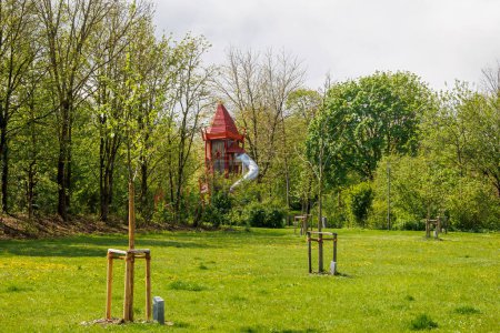 Foto de Un parque infantil con una torre de juego de color rojo brillante y tobogán en Konigsbrunn cerca de Augsburgo en Baviera en un día nublado - Imagen libre de derechos