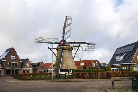 Foto de Un molino de viento de pólder histórico para drenar las zanjas en una zona residencial en Den Oever, Países Bajos, 24.3.2024 - Imagen libre de derechos