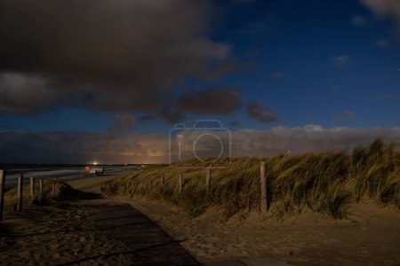 Téléchargez les photos : Dunes sur la plage près du monument Pettendorf aux Pays-Bas la nuit avec une pleine lune - en image libre de droit