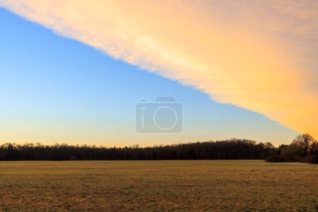 Colorida banda de nubes en el cielo matutino sobre los campos y prados de Siebenbrunn, el distrito más pequeño de la ciudad de Fugger de Augsburgo
