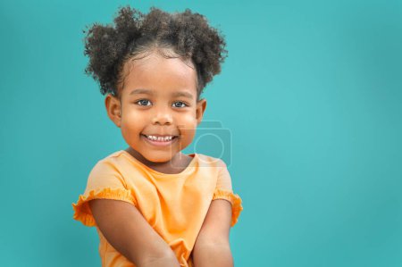 Téléchargez les photos : Douce petite fille en plein air avec les cheveux bouclés souriant sur fond bleu - en image libre de droit