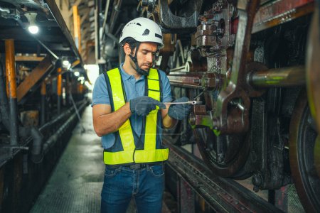 Téléchargez les photos : Travailleur travaillant dans une usine industrielle utilise un tournevis croisé pour inspecter la machine. - en image libre de droit