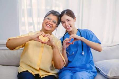 Téléchargez les photos : Une jeune infirmière et une personne âgée donnent un pouce vers le haut montrant la bonne santé du traitement des personnes âgées - en image libre de droit
