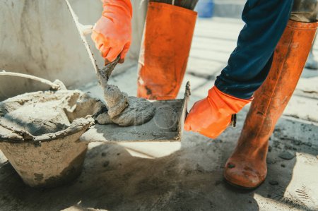 Téléchargez les photos : Gros plan main de travailleur plâtrage ciment au mur pour la construction de la maison - en image libre de droit