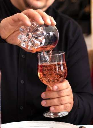 Foto de Young man pouring wine from the bottle into a glass . wine at restaurant. High quality photo - Imagen libre de derechos