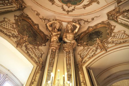 Foto de Queluz, Lisboa, Portugal- 17 de enero de 2023: Atlases y refinada decoración en madera dorada del hermoso Palacio Nacional de Queluz, Sintra - Imagen libre de derechos
