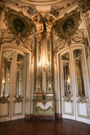 Foto de Queluz, Lisboa, Portugal- 17 de enero de 2023: Lámparas de araña francesas, muebles y refinada decoración de madera dorada del hermoso Palacio Nacional de Queluz, Sintra - Imagen libre de derechos