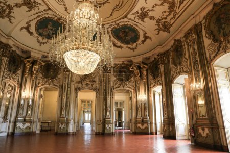 Foto de Queluz, Lisboa, Portugal- 17 de enero de 2023: Lámparas de araña de cristal, muebles y refinada decoración de madera dorada del hermoso Palacio Nacional de Queluz, Sintra - Imagen libre de derechos