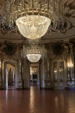 Foto de Queluz, Lisboa, Portugal- 17 de enero de 2023: Lámpara de araña de cristal, muebles y decoración de madera dorada refinada del hermoso Palacio Nacional de Queluz, Sintra - Imagen libre de derechos