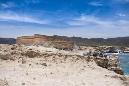 Foto de Cabo de Gata, Almería, España- 17 de junio de 2023: Fortaleza de piedra construida sobre duna fosilizada en la playa de Escullos en Cabo de Gata - Imagen libre de derechos
